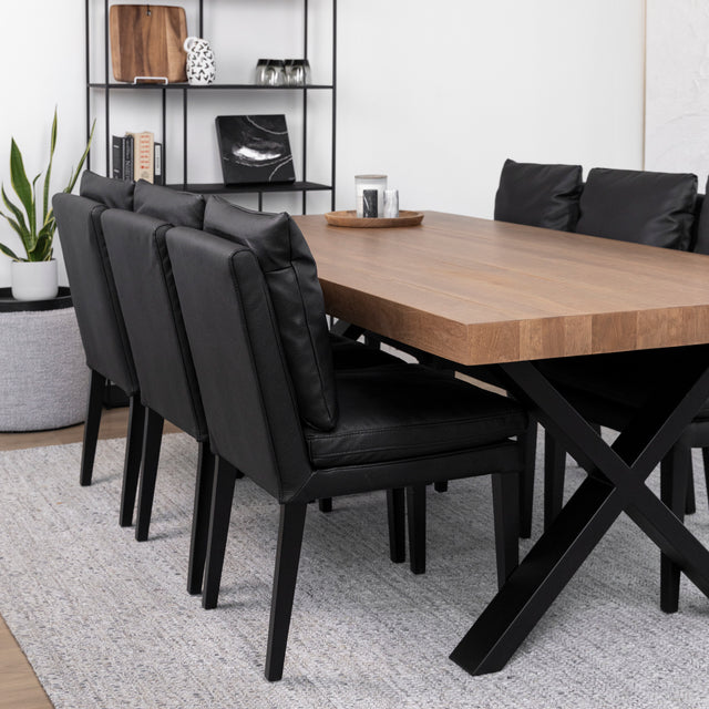 Salle a manger moderne avec table en bois, chaises noires et pieds croises en metal.