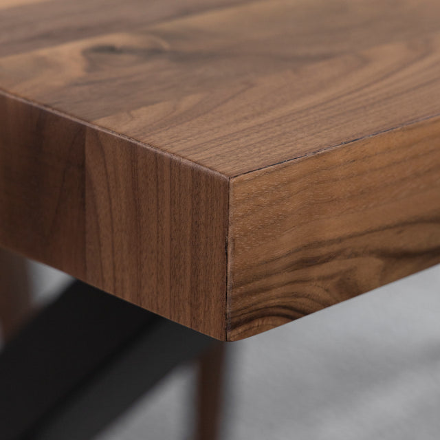 Gros plan sur table en bois massif avec details de veinure naturelle et chaise beige.