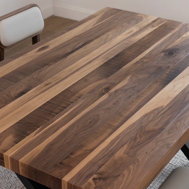 Table en bois a bandes contrastees avec chaises beige et meuble assorti en fond.