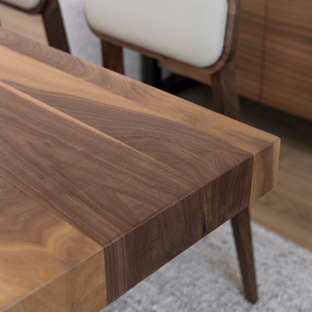 Gros plan sur table en bois massif avec details de veinure naturelle et chaise beige.