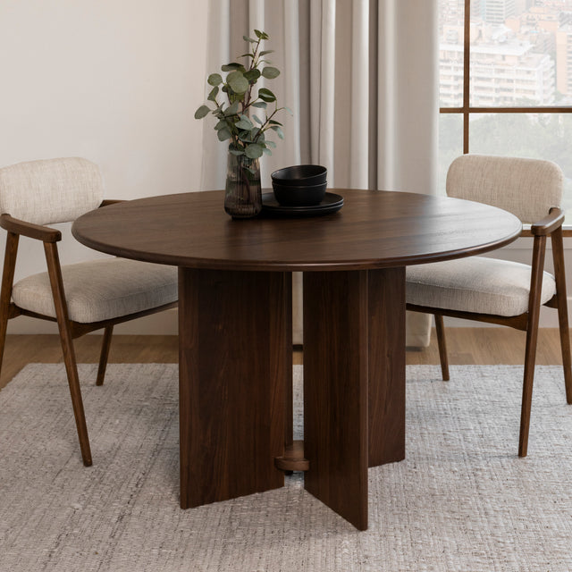 table ronde en bois fonce avec pied central et chaises beige au style moderne.