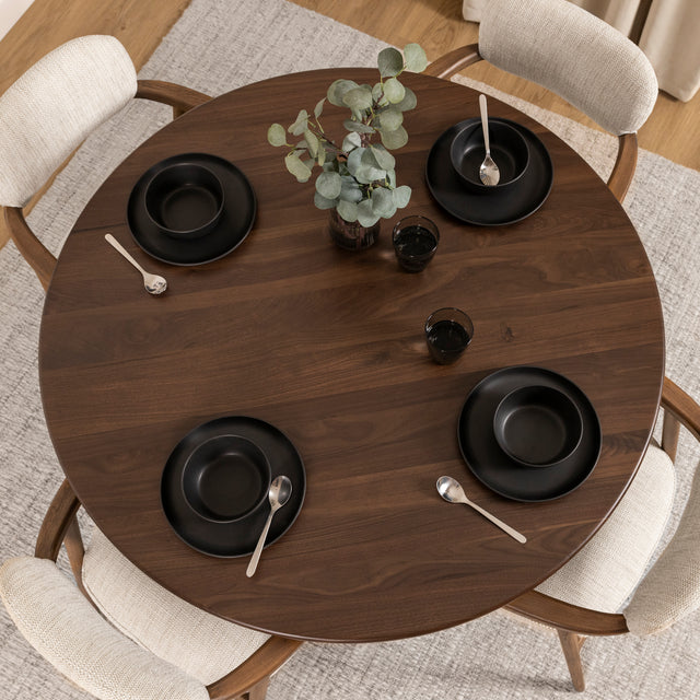 Table à manger ronde en bois foncé avec fauteuils bouclés beige style scandinave.