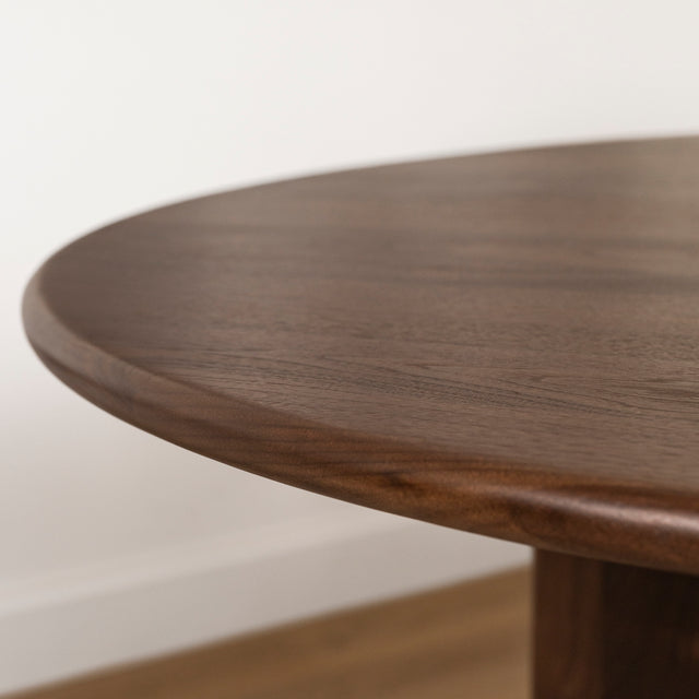 bord arrondi de table ronde en bois fonce avec finition lisse et elegante.