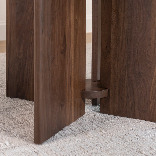 détail du pied central en bois foncé d’une table ronde au design contemporain.