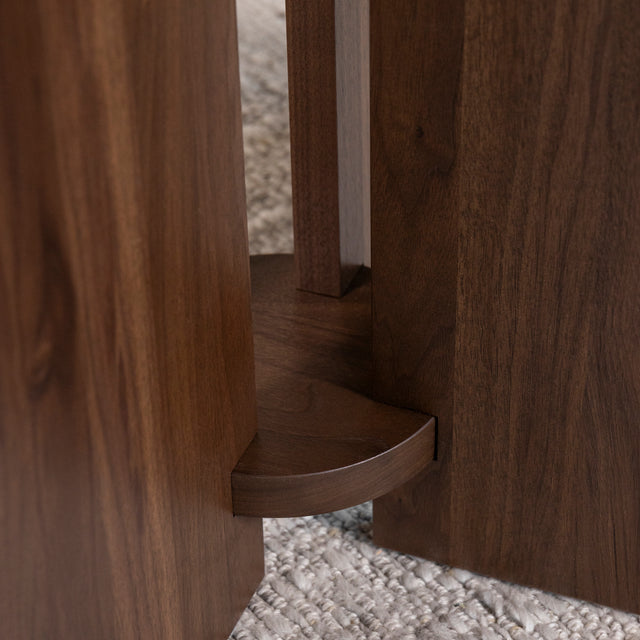 détail du pied central en bois foncé d’une table ronde au design contemporain.