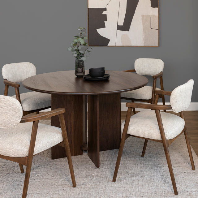 table ronde en bois fonce avec chaises tissu beige et accoudoirs bois.