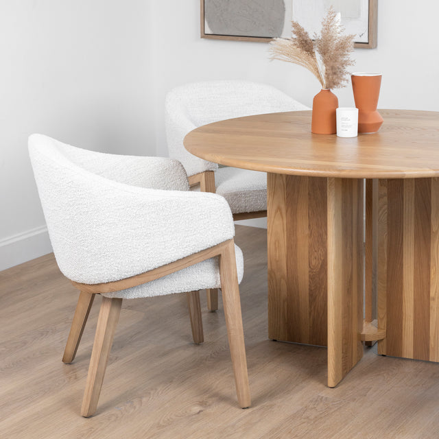 table ronde en bois clair avec pied central et chaises boucle beige modernes.