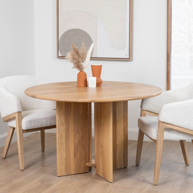 table ronde en bois clair avec pied central et chaises boucle beige modernes.