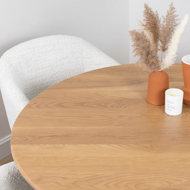 table ronde en bois clair avec decoration en vases terracotta et chaise boucle beige.