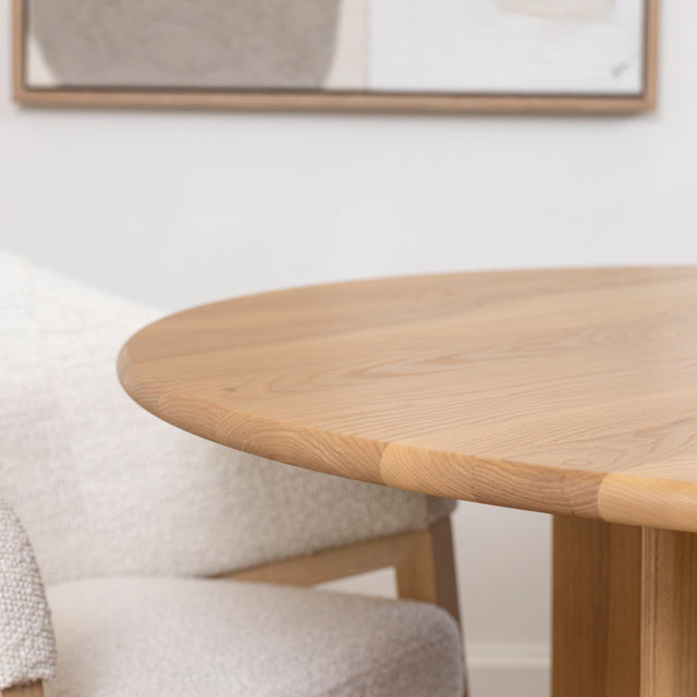 bord arrondi de table ronde en bois clair avec chaise en tissu boucle beige.