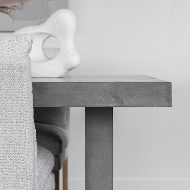 table en beton gris avec sculpture blanche et chaises textiles claires.