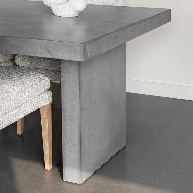 pied central de table en beton gris avec chaises claires et sol moderne.