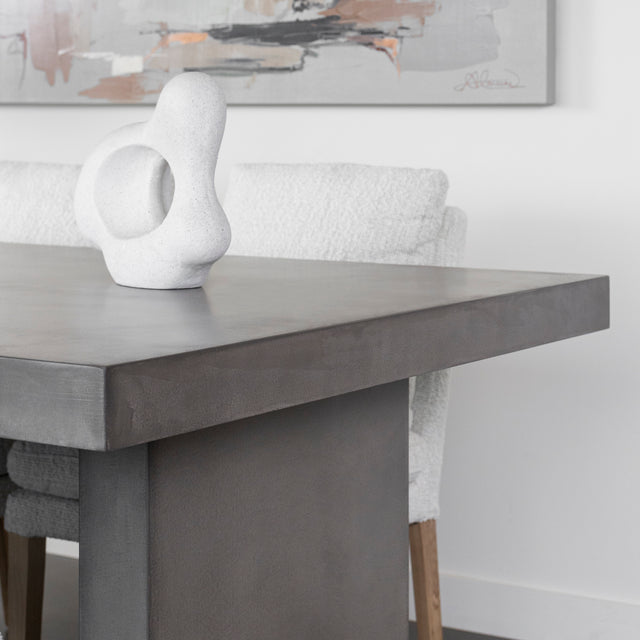 table en beton gris avec sculpture decorative blanche et chaises claires.