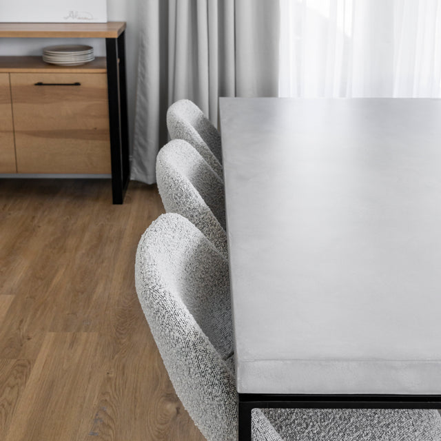 table en beton clair avec chaises grises texturees et sol en bois clair.