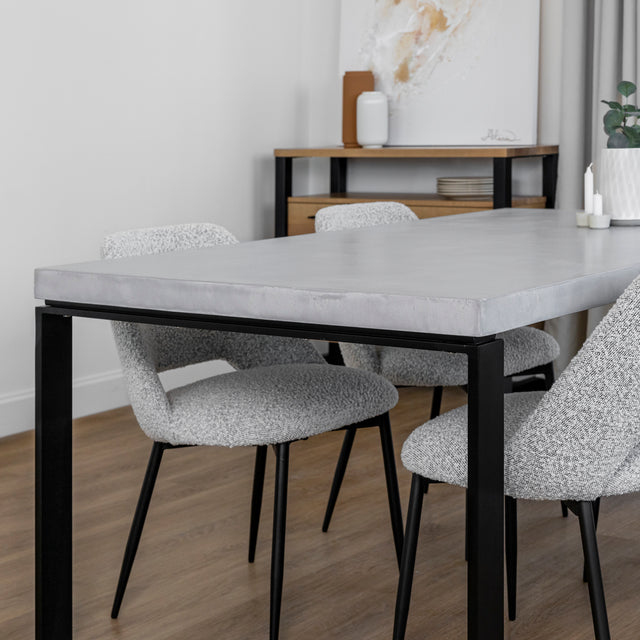 table en beton clair avec pieds noirs et chaises grises au style moderne.