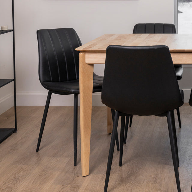 coin d’une table en bois clair avec chaises noires au design contemporain.