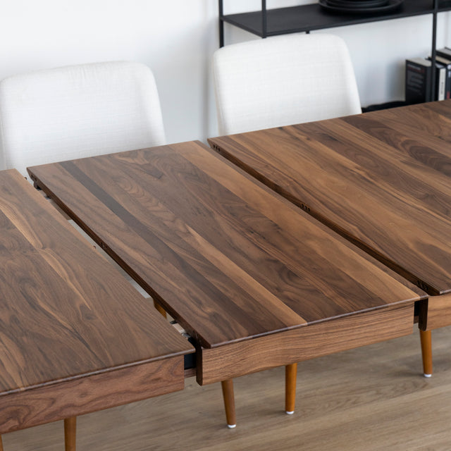 Rallonge centrale en bois noyer installee sur table extensible au design moderne et chaleureux.