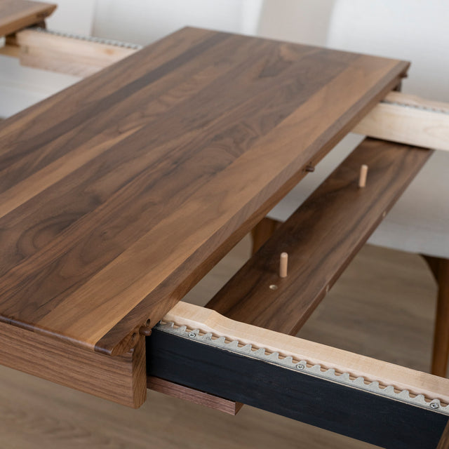 Detail du mecanisme d’extension d’une table en bois noyer avec rallonge centrale ajustable.