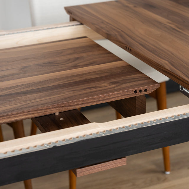 Table a manger en bois noyer avec rallonge centrale extensible sur sol en parquet clair.