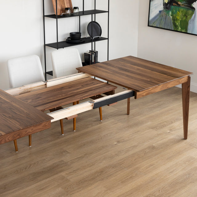 Table a manger en bois noyer avec rallonge centrale extensible sur sol en parquet clair.