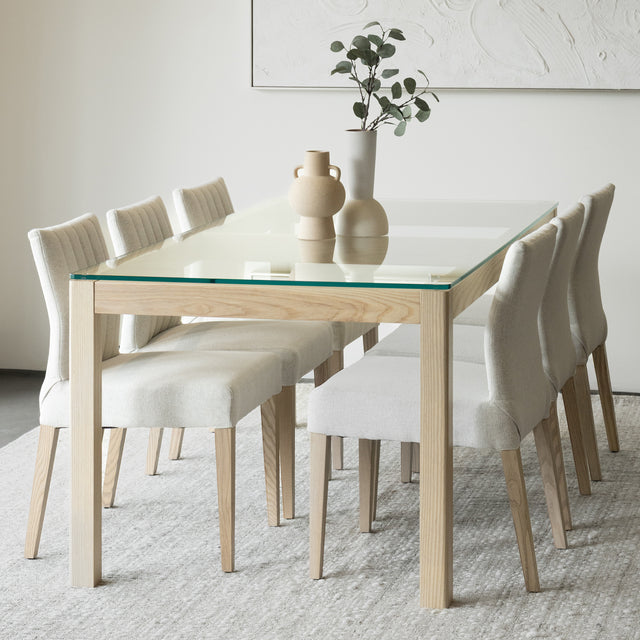 Salle a manger elegante avec table en verre et bois clair et chaises beige modernes.
