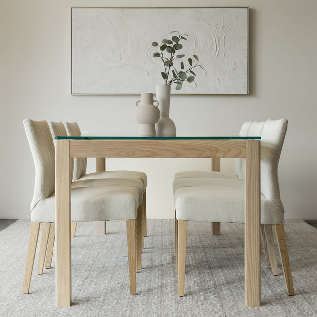 Salle a manger elegante avec table en verre et bois clair et chaises beige modernes.