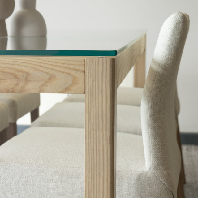 Gros plan sur table en verre et bois clair avec chaises beige au design epure.