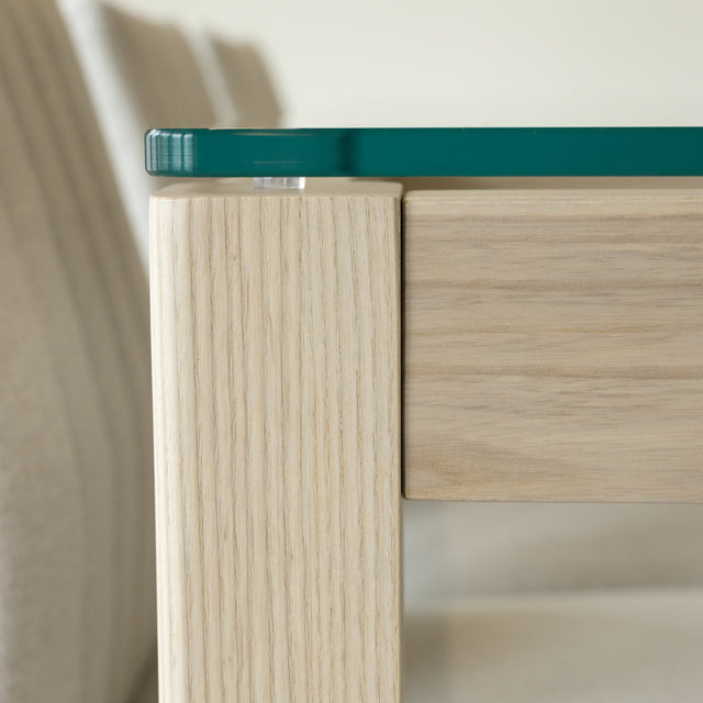 Detail d angle de table en verre et bois clair avec fixation elegante et finitions soignées.