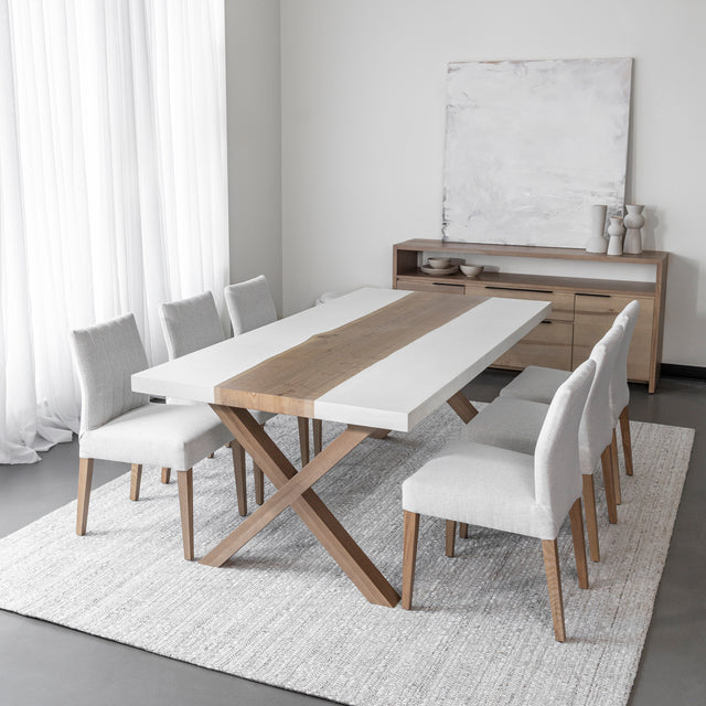 table de salle a manger moderne avec plateau en bois et resine blanche, pieds croises en bois clair et chaises beige sur tapis tissé clair.
