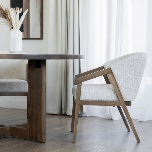Table ronde en bois avec chaises beige et vase blanc dans deco lumineuse et epuree.