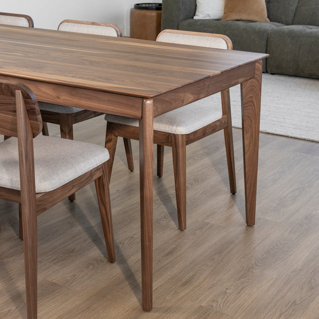 Table en bois noyer avec chaises beiges tapissees sur parquet clair dans decor moderne.