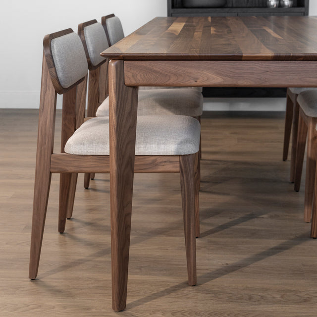 Table en bois noyer avec chaises beiges tapissees sur parquet clair dans decor moderne.