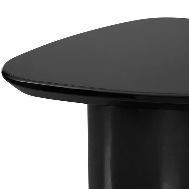 Gros plan sur une table d’appoint noire brillante, montrant son plateau aux bords arrondis et sa base cylindrique lisse.