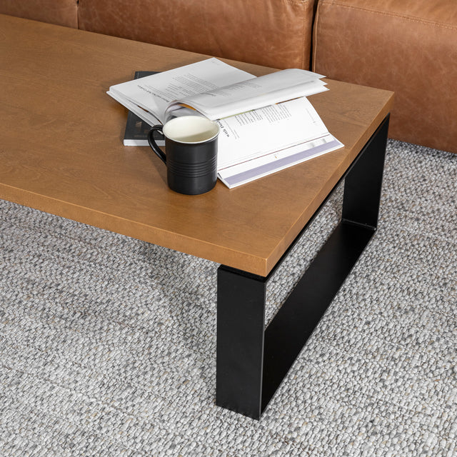 table basse rectangulaire en bois et metal noir avec tasse et livres dans un salon moderne.