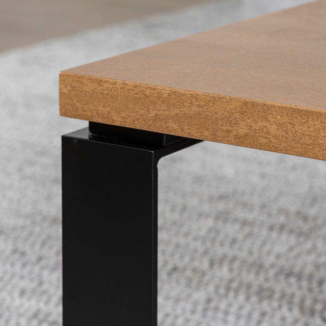 Coin de table basse en bois clair avec pied en metal noir sur tapis gris.