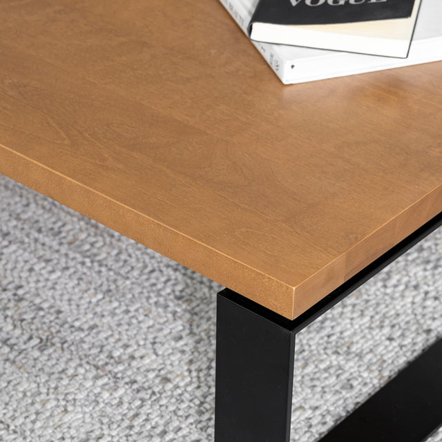 Table basse en bois clair avec pied en metal noir sur tapis gris moderne.