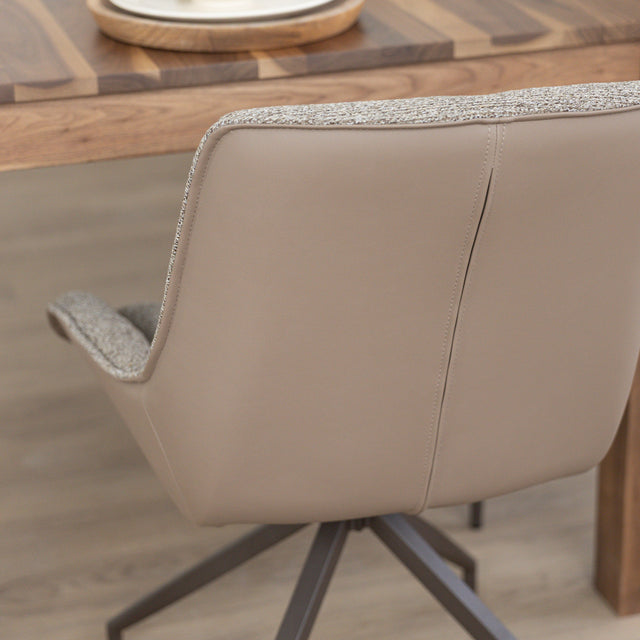 Chaise de salle à manger tissu chocolaté avec piétement en métal bronze, placée près d’une table en bois moderne.