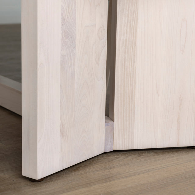 Image rapprochée du pietement d'une table ovale en bois clair.