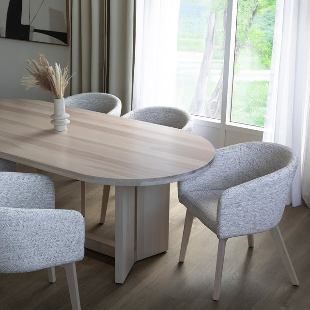 Table ovale en bois clair avec chaises crème modernes dans salle a manger lumineuse.