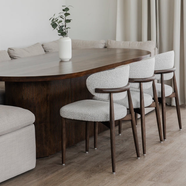 Salle a manger moderne avec table ovale en bois fonce et chaises beige sur plancher clair.
