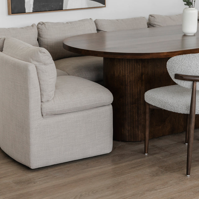 Table ovale en bois fonce avec banquette grise et chaise beige dans deco moderne.