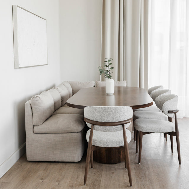 Table ovale en bois fonce avec banquette grise et chaise beige dans deco moderne.