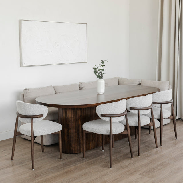 Salle a manger moderne avec table ronde en bois fonce et chaises tissu beige elegantes.
