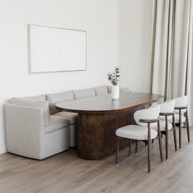 Salle a manger elegante avec table ovale en bois fonce, chaises beige et banquette grise.