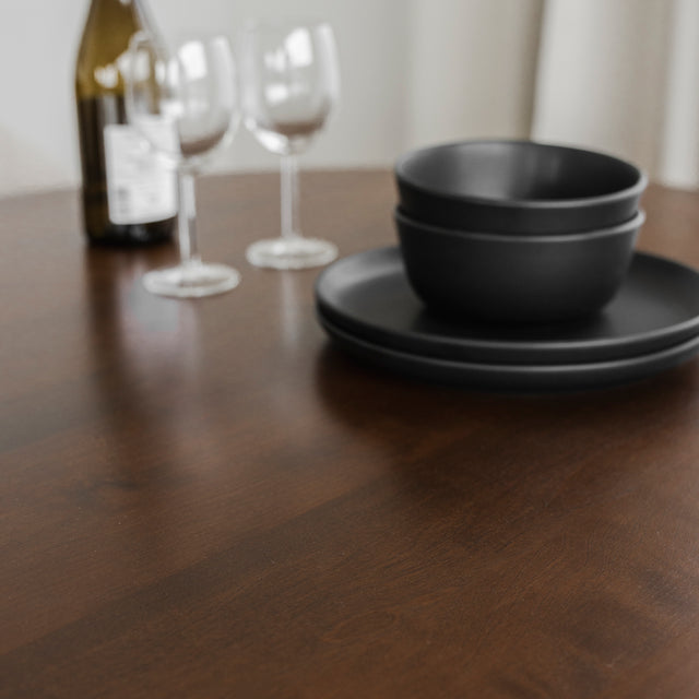 Table en bois fonce avec vaisselle noire et verres a vin pour deco elegante.