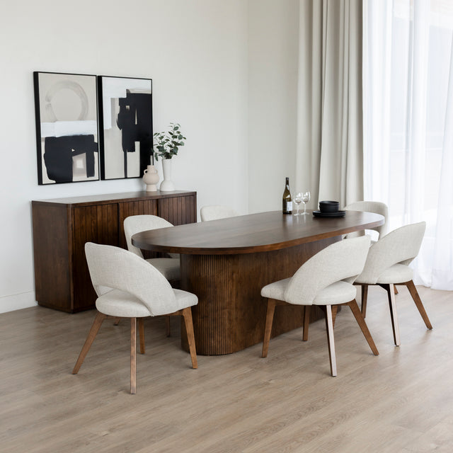 Salle a manger moderne avec table ovale en bois fonce et chaises beige sur plancher clair.