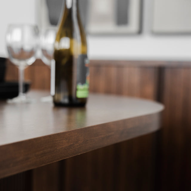 Gros plan sur table en bois fonce avec verres et bouteille dans deco moderne.