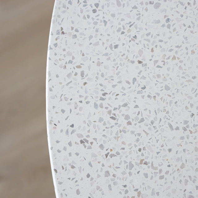 image rapprochée d'une table ronde blanche au plateau en terrazzo et base sculpturale.