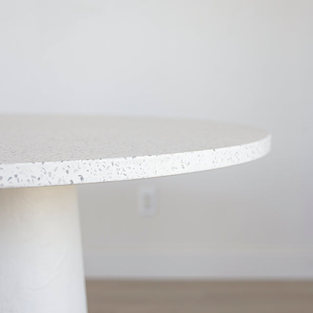 table ronde blanche au plateau en terrazzo et base sculpturale.