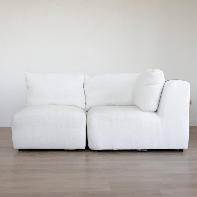 Canape d’angle blanc en tissu bouclette avec assises profondes et coussins moelleux sur parquet clair.